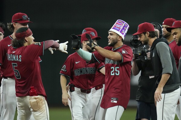 Arizona Diamondbacks' Adrian Del Castillo (25) celebrates his walk-off single against the Cleveland Guardians with teammates, including Alek Thomas (5) and Zac Gallen, right, after a baseball game Wednesday, Aug. 20, 2025, in Phoenix. (AP Photo/Ross D. Franklin)