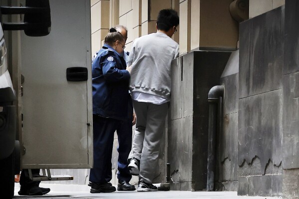 Trainee surgeon, Ryan Cho is escorted into the Supreme Court of Victoria in Melbourne, Australia, Friday, Aug. 22, 2025. (Con Chronis/AAP Image via AP)
