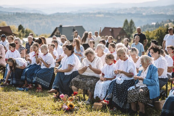 Women practice "hekla", the traditional art of hand-crocheted lace making, on a valley slope in the village of Koniakow, Poland, Sunday, Aug. 17, 2025. (AP Photo/Daniel Franek)