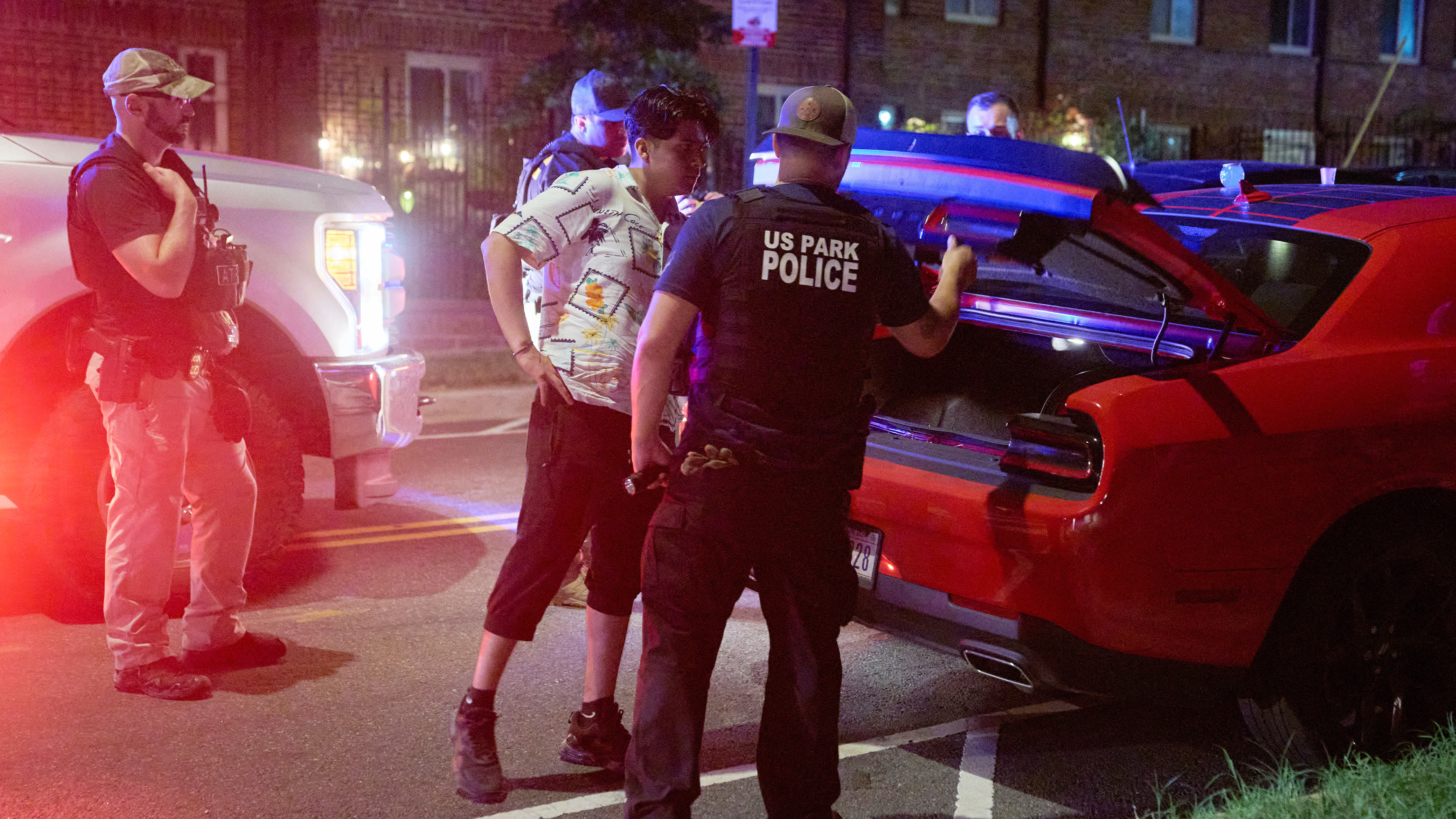 Agents from various agencies including Bureau of Alcohol, Tobacco, Firearms and Explosives, Park Police, and FBI, question a couple who had been parked outside a legal parking zone while eating McDonald's takeout, Tuesday, Aug. 12, 2025.